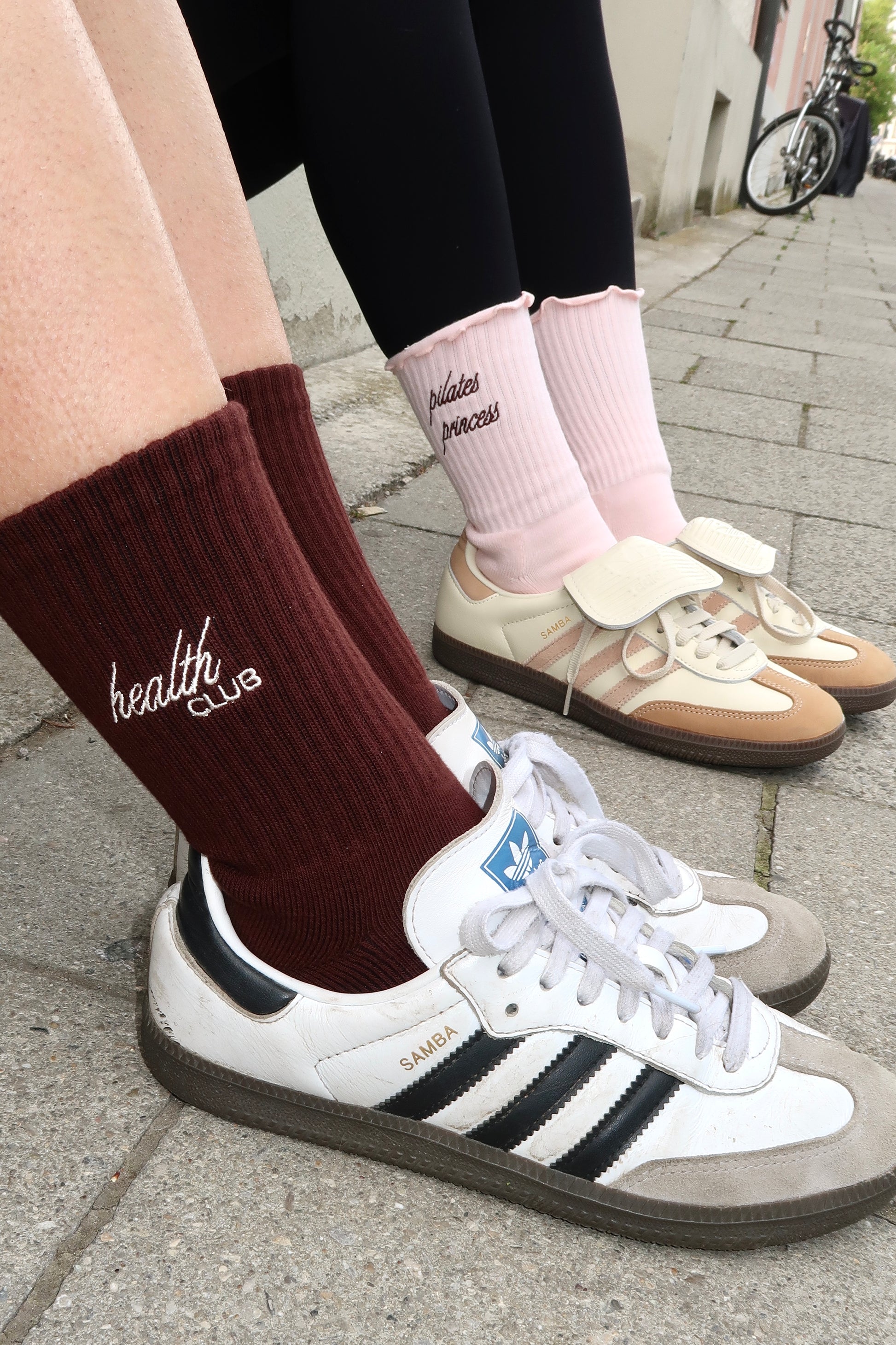 Braune „Health Club“-Socken und rosa „Pilates Princess“-Socken, kombiniert mit Retro-Sneakern, Straßenaufnahme