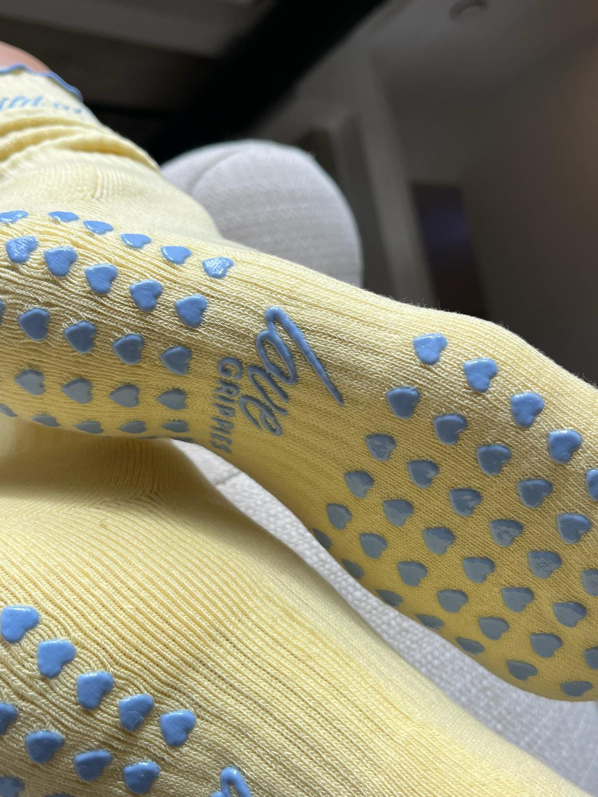 Butter yellow Pilates-Socken mit blauen Herz-Anti-Rutsch-Noppen und love-grippies Logo auf der Sohle