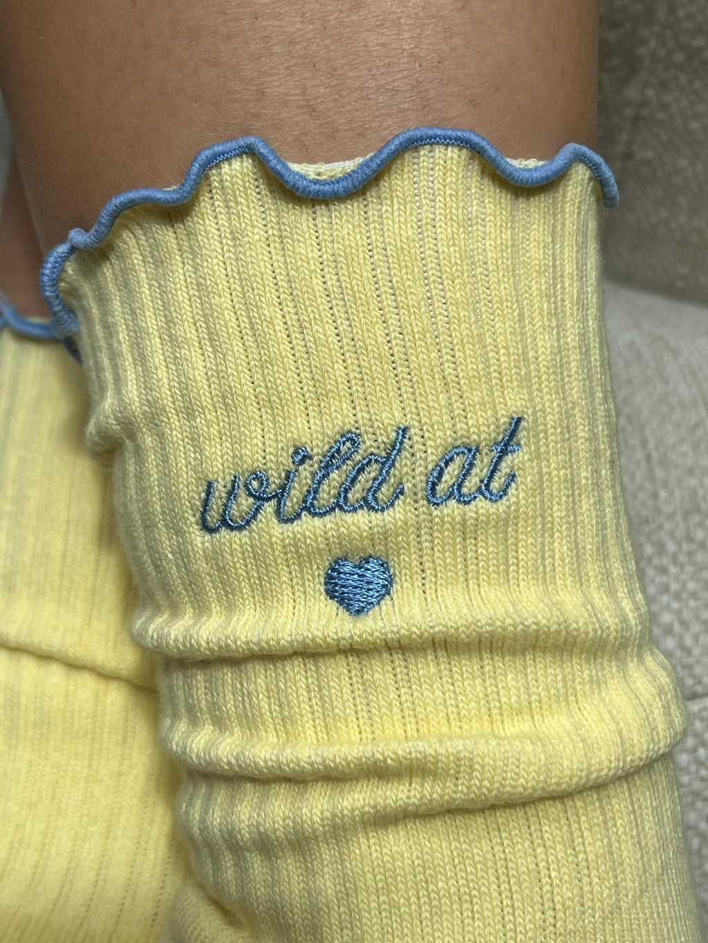 Detailansicht butter yellow Socke mit blauer Stickerei "wild at heart" und Herzsymbol