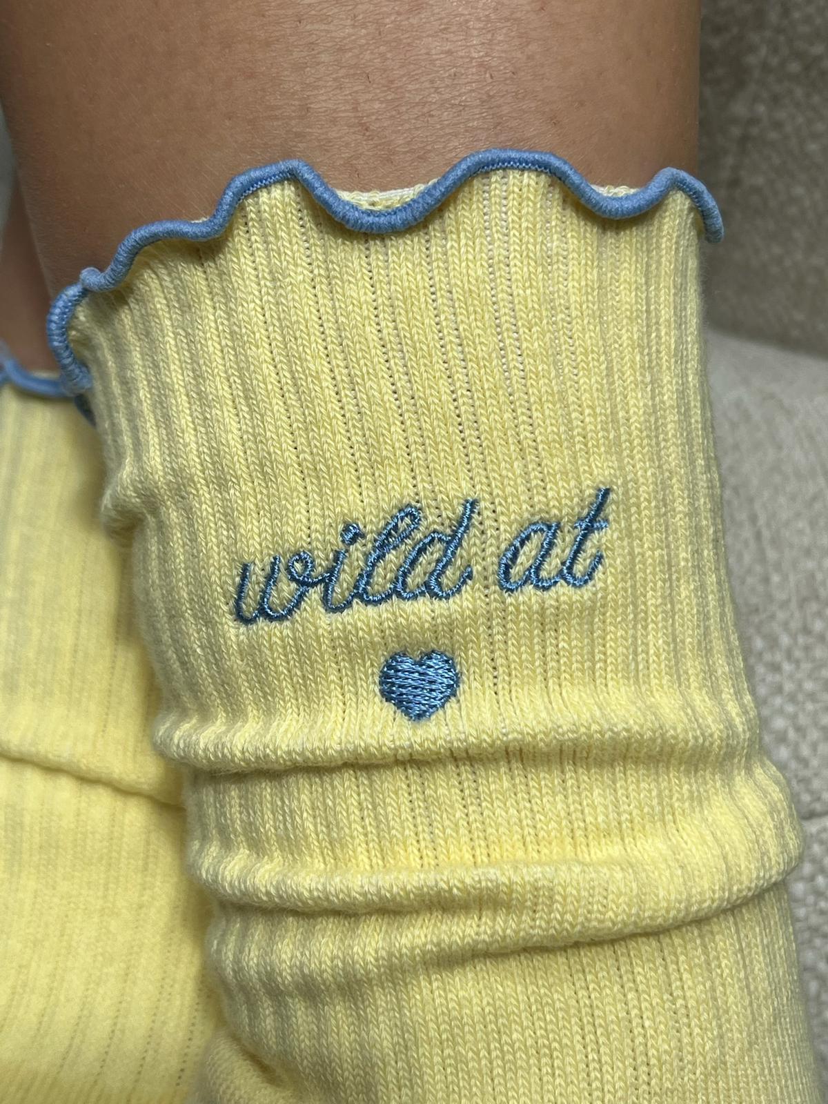 Detailansicht butter yellow Socke mit blauer Stickerei "wild at heart" und Herzsymbol